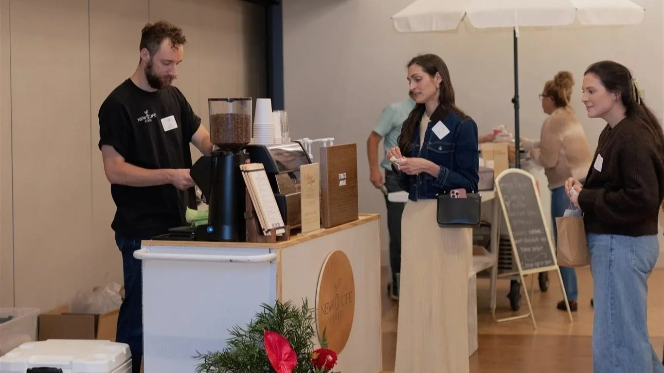 Barista handing a finished drink to a guest at a mobile coffee bar