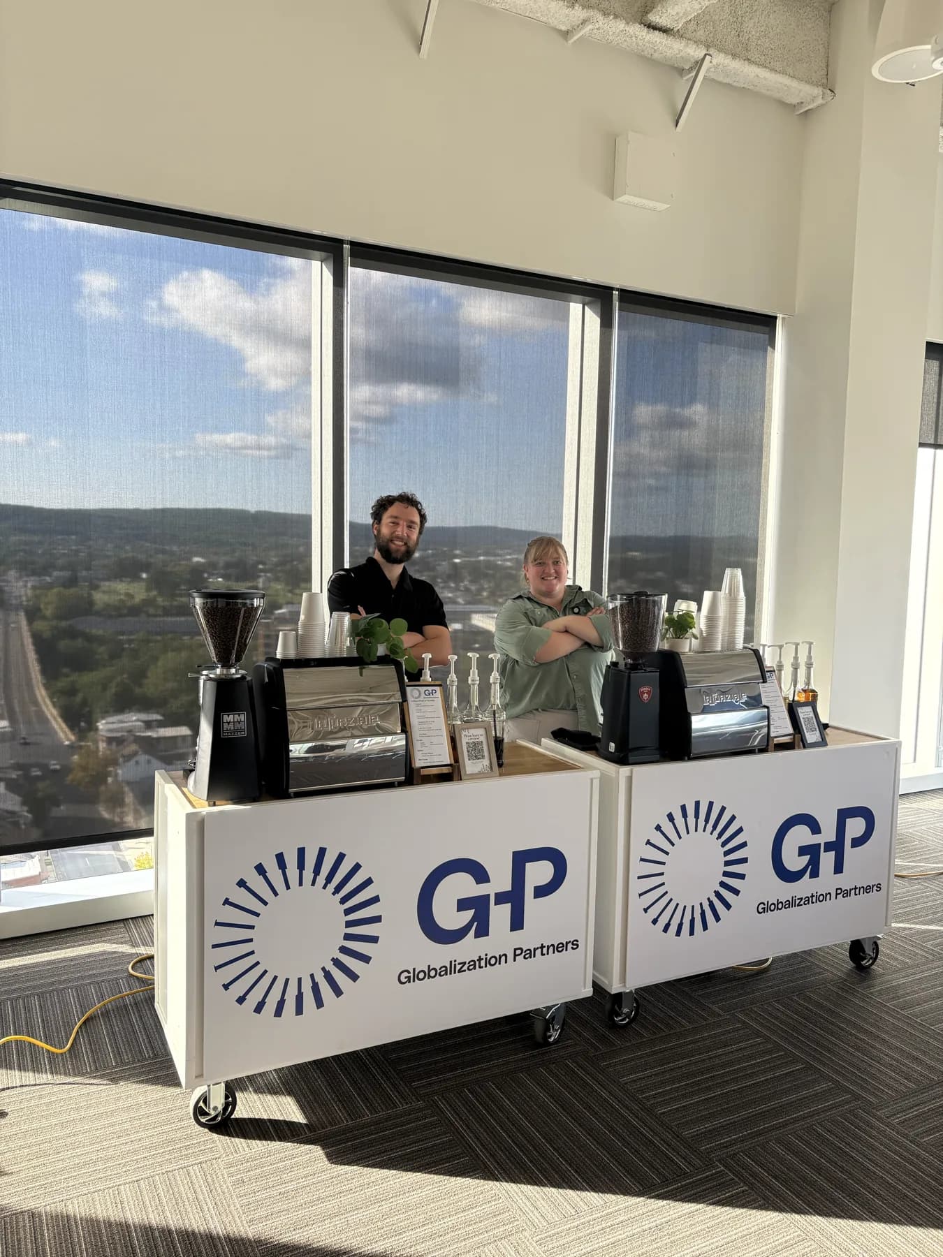 Two New Life Coffee Company baristas behind twin coffee carts wrapped in Globalization Partners branding