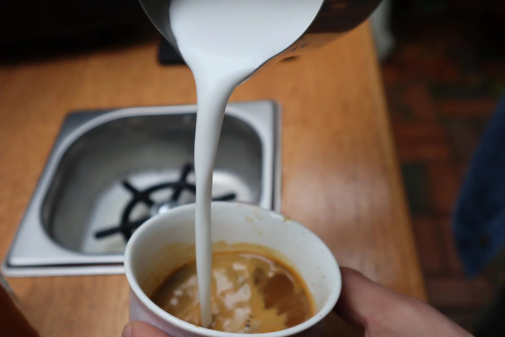 Barista pouring steamed milk into a latte at a New Life Coffee Company event